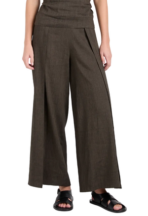 The lower half shows a person wearing Proenza Schouler White Label’s Calla Slub Linen Pant in dark brown—a cropped, wide-leg style with subtle texture and front pleats—paired with black sandals for an airy silhouette.