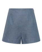 Front view of POSSE's Thea Short in blue chambray linen, showing its subtle textured pattern, flat waistband, and adjustable tabs for a custom fit.