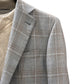 A close-up of the Canali Kei Lined Grey/Brown Plaid Blazer with a notch lapel, styled over a beige textured sweater.
