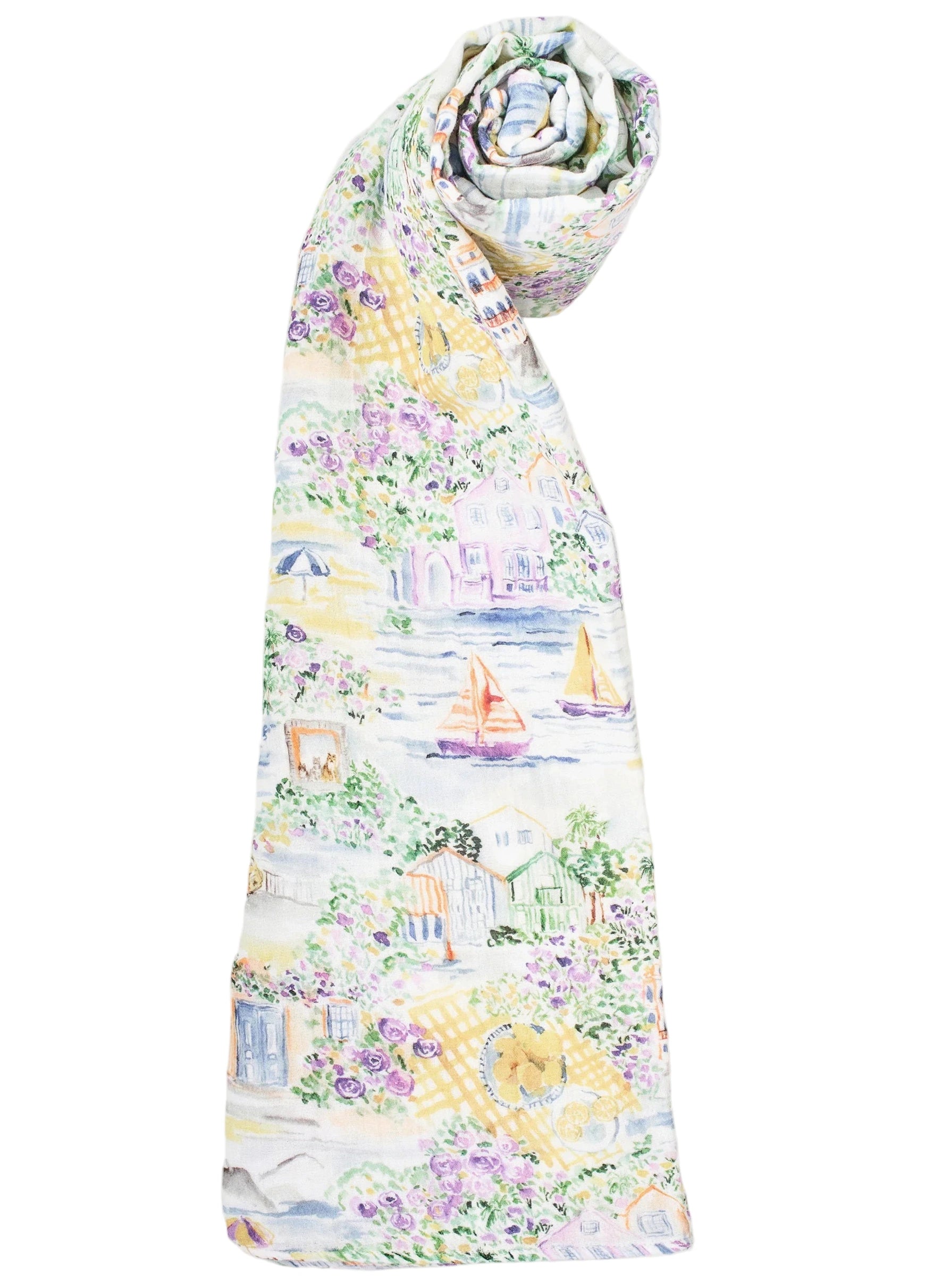 The Timo & Violet Shawl Blanket features a colorful, coastal print with houses, flowers, sailboats, and umbrellas on a white background.