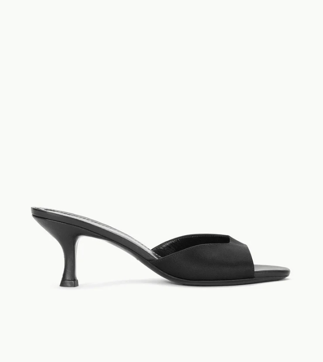 The Staud Brigitte Satin Mule, a black open-toe sandal with a mid-height stiletto heel, is shown in profile against a white background—ideal for versatile styling.