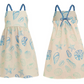 Front and back views of the Pepita & Me Girls' Isleno Dress, a cream summer dress with blue braided straps and blue seashell and starfish prints for a comfortable fit.