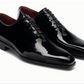 A pair of Cruz II Tux black patent leather oxford dress shoes with laces by Magnanni, featuring a glossy finish and low heel, displayed on a white background—ideal for enhancing any formal look.