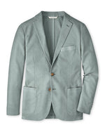 The Peter Millar Weekend Soft Jacket is a light gray-blue men's cotton-stretch blazer featuring two brown buttons, notch lapels, three front pockets, and a subtle textured fabric, shown against a plain white background.