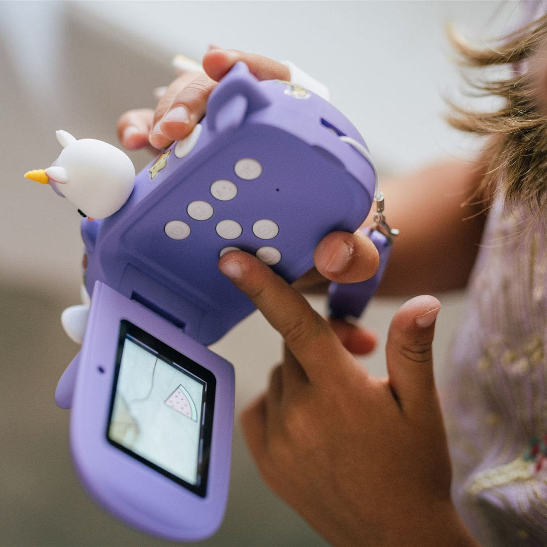 A child playing a game on a Kidamento Digital Camera Model V, Iris the Unicorn, their excitement mirrored in the built-in selfie camera.