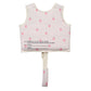 Sunnylife Kids' Swim Vest in pink and white, adorned with strawberry prints and shown from the back, features a neoprene comfort guard for extra coziness and an anti-rise safety strap with a warning label near the bottom.