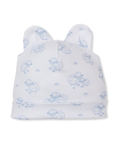 The Sweet Sheep Hat by Kissy Kissy is a white baby hat adorned with a blue sheep print, made from soft Pima cotton and accented with two small fabric ears on top.