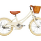 The Banwood Classic Children’s Bicycle is cream-colored with a brown seat, cream tires, and a wicker basket on the front handlebars, displayed in profile against a white background.