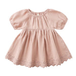 The Quincy Mae Baby Girls' and Girls' Bella Dress is a light pink dress with short sleeves, gathered waist, scalloped hem with eyelet embroidery, round neckline, and a loose fit.