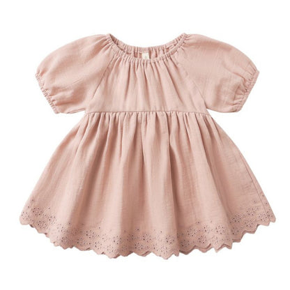 The Quincy Mae Baby Girls' and Girls' Bella Dress is a light pink dress with short sleeves, gathered waist, scalloped hem with eyelet embroidery, round neckline, and a loose fit.