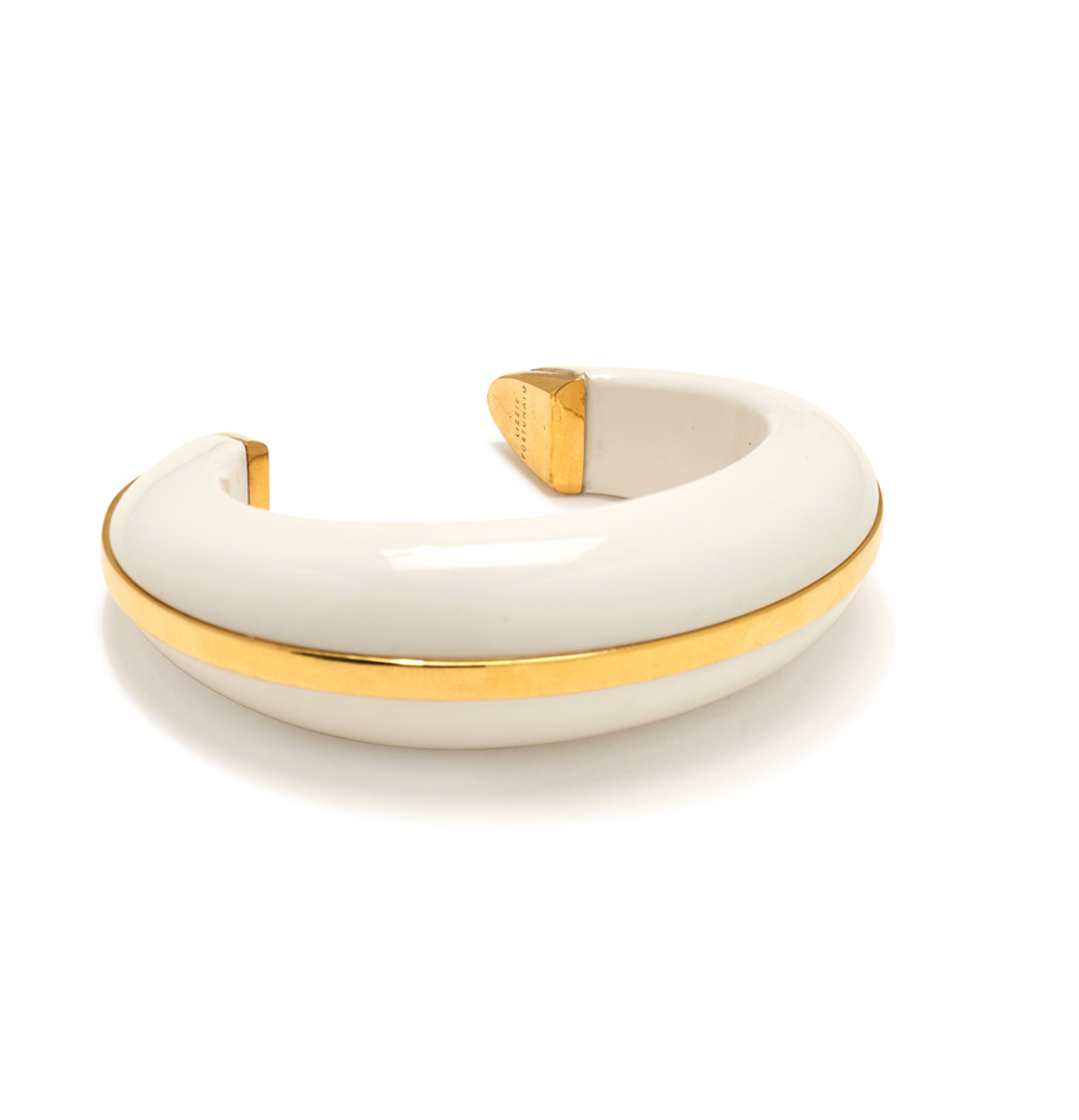 The “Halo Cuff” by Lizzie Fortunato is a white and gold open-ended bangle bracelet featuring a smooth, rounded design reminiscent of an alabaster bracelet, photographed on a plain white background.