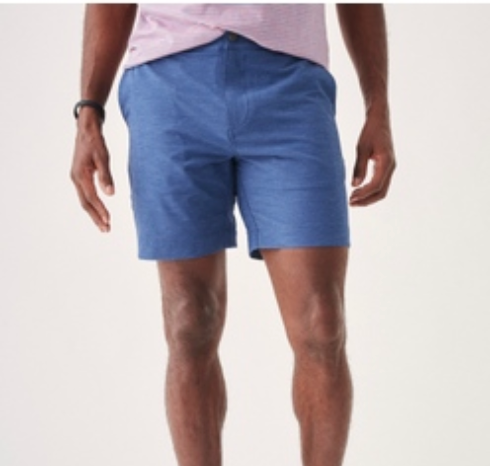 A person wears a light pink shirt and Faherty Belt Loop All Day Shorts, 7", in blue, made from eco-friendly fabric, standing against a plain background with only their torso and upper legs visible.