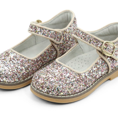 The L'Amour Shoes L'Amour Natasha Glitter Mary Jane is a dazzling pair of shoes featuring glitter-covered material, buckle straps, and light tan soles, ideal for adding sparkle to any outfit.