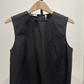 The Linen Crew Neck Shell Tank by vince is a sleeveless black top crafted from a lightweight, breathable linen blend, shown on a wooden hanger against a plain white background.