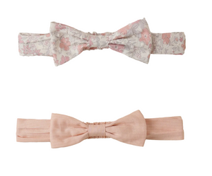 The Baby Girls’ Bow Headband Set by Noralee features two stretchy headbands—one with a pink floral pattern and one in solid pale pink—both displayed on a white background, offering comfort and style to any little one’s wardrobe.