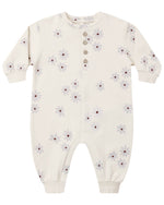 The Quincy Mae Baby Relaxed Fleece Jumpsuit features a cream color, long sleeves, delicate floral pattern, five front buttons, and ribbed cuffs at the wrists and ankles. This cozy essential is perfect for everyday comfort.