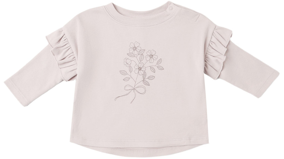 The Quincy Mae Baby Girls’ and Girls’ Ruffle Long Sleeve Tee is a cozy everyday essential, featuring a light pink hue, charming ruffled shoulders, and a delicate line drawing of flowers tied with a bow on the front.