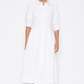 A person wears a white, long-sleeve, button-down Signature Jazz Dress by Simkhai, made from cotton poplin, against a plain background.