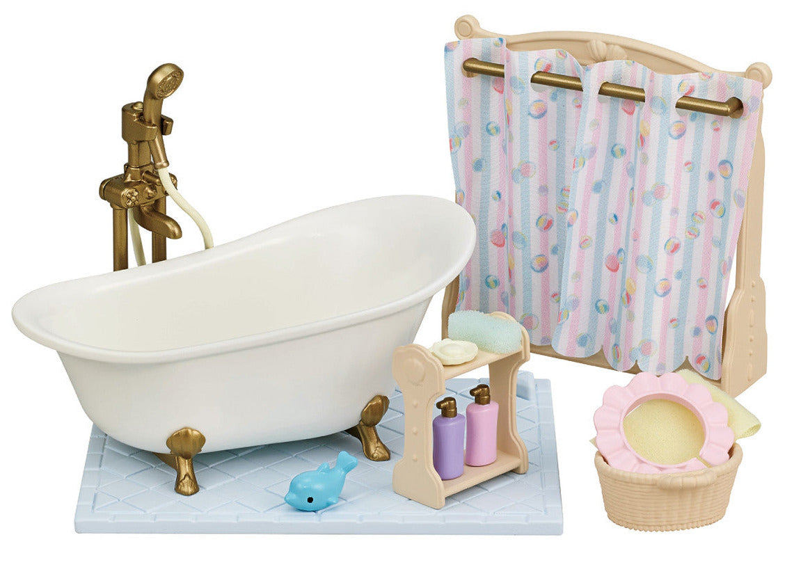 The Calico Critters Bath & Shower Set features an antique-style bath fitting, charming clawfoot tub, shower curtain, shelf with bottles, blue toy whale, laundry basket, and sponge on a tiled mat—an adorable collection of bath time accessories to enhance your dollhouse furniture set.