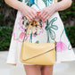 A person in a Lela Rose Lela Rose Embroidered Canvas Mini Dress adorned with floral embellishments holds a small yellow handbag in front of them.