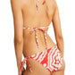 A true swimwear staple, the person wears a Lemlem Malia Triangle Top and Rekka String Bottom in red and white patterns, seen from the back.