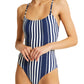 A person is wearing the Lemlem Elene One Piece by Lemlem, featuring adjustable spaghetti straps and a classic blue and white striped design, standing against a plain background.