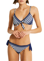 Someone wearing the Lemlem Sara Tie Front Top and Lucy Bottom, a navy and white striped bikini with adjustable spaghetti straps and side tie bottoms.