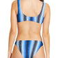 A woman is shown from the back wearing the Lemlem Jalene Top and Taitu Bottom Bikini, a blue, black, and white striped set with a moderate coverage bralette swim top.