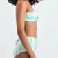 Woman in Lemlem's Ava Bandeau Top and Elsi High Waist Bottom, a strapless light blue and white striped bikini set, stands in profile against a plain background.