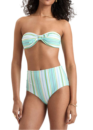 A woman wears Lemlem’s Ava Bandeau Top with a twist detail and matching Elsi High Waist Bottom, both in pastel stripes.