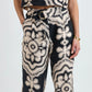 Wearing Lemlem’s Diarra Pant—black and beige patterned, relaxed straight-leg—paired with a sleeveless belted top, one hand in pocket.