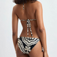 A woman is shown from the back wearing Lemlem’s Malia Top and Rekka Bottom Bikini—a stylish black and white patterned triangle top with tie straps and a matching string bikini bottom.