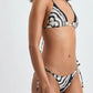 A woman models the Lemlem Malia Top and Rekka Bottom Bikini in a black and white pattern, viewed from the side against a plain background.