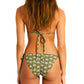 A person with hair down poses in a Lemlem Malia Top and Rekka Bottom Bikini, featuring white floral patterns on green and adjustable string ties, against a plain background.
