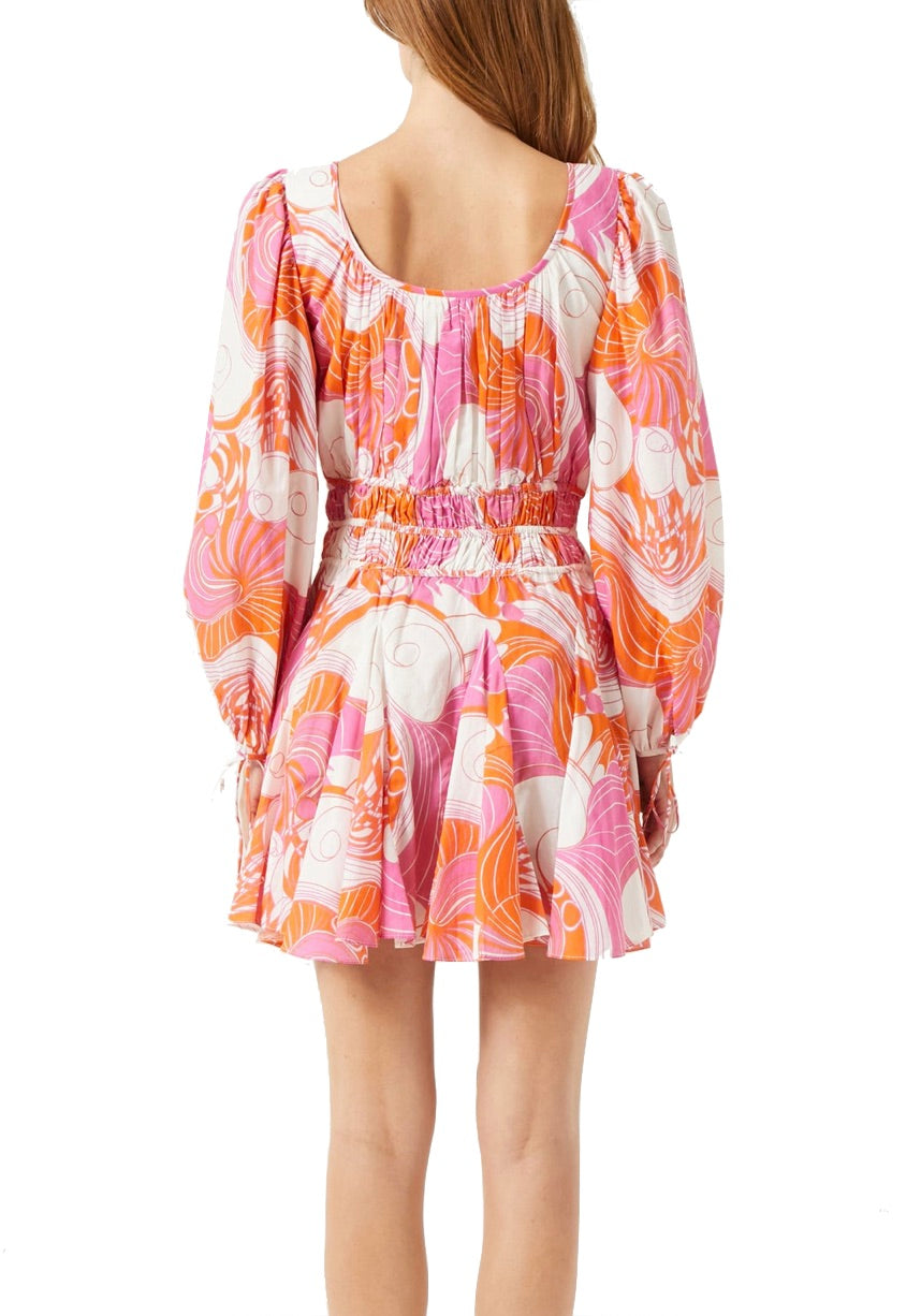 A woman is shown from the back wearing the Rhode Leona Dress, a long-sleeve, colorful floral design in Pink Deco Surf print with a cinched waist and a flared skirt, crafted from Cotton Cambric Fabrication.