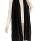 A woman wearing the Alashan Cashmere Luxe Travel Wrap elegantly draped over a beige sweater and light-colored pants, standing against a plain background.