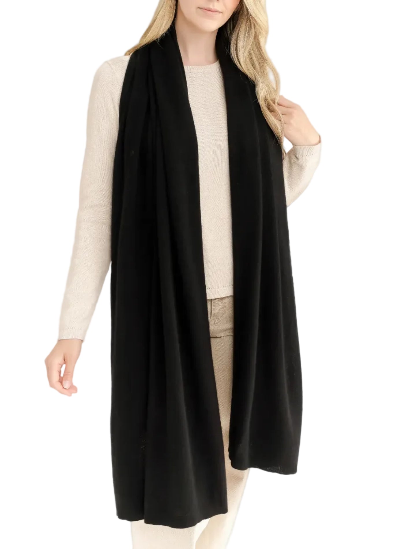 A woman wearing the Alashan Cashmere Luxe Travel Wrap elegantly draped over a beige sweater and light-colored pants, standing against a plain background.