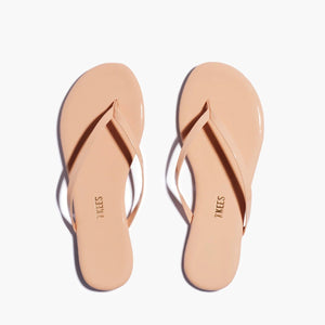 Lily Glosses Sandals by Tkees are nude flip-flops with thin straps, crafted from luxurious Brazilian leather and displayed on a plain white background.
