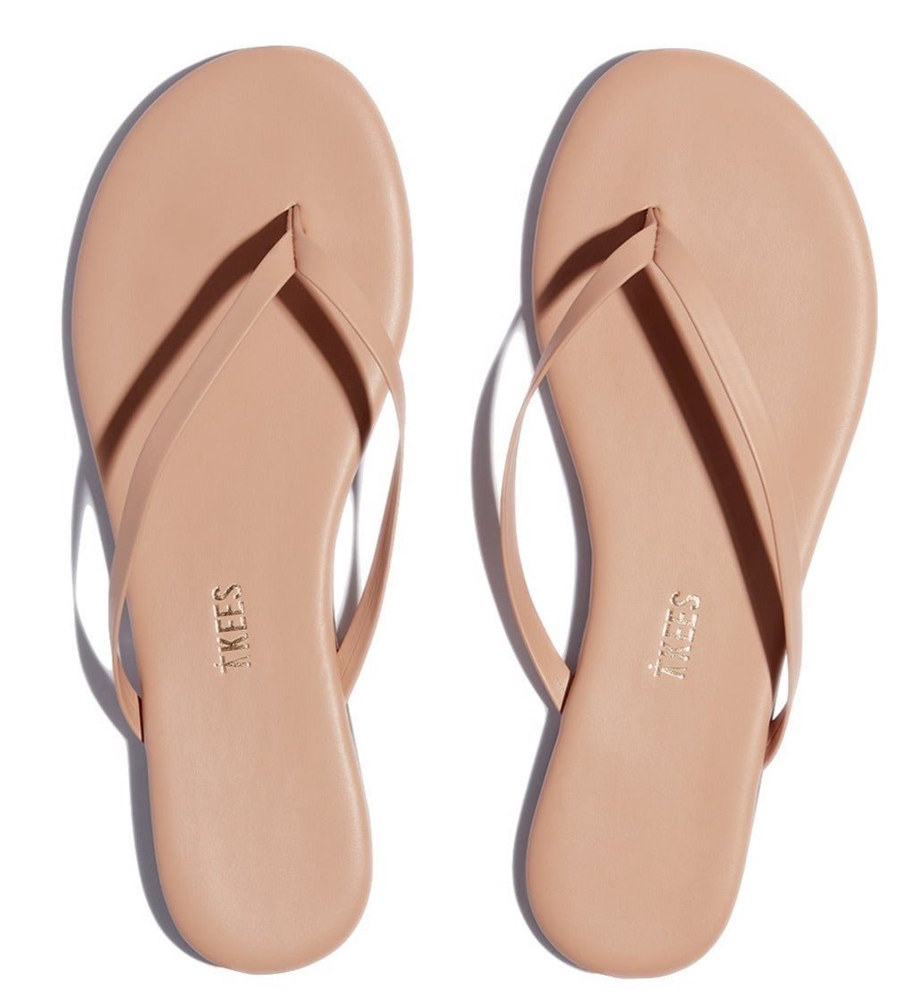 A pair of nude Tkees Lily Nudes Sandals from the Tkees Nude collection with the words 'node beach'.