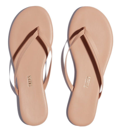 A pair of nude Tkees Lily Nudes Sandals from the Tkees Nude collection with the words 'node beach'.