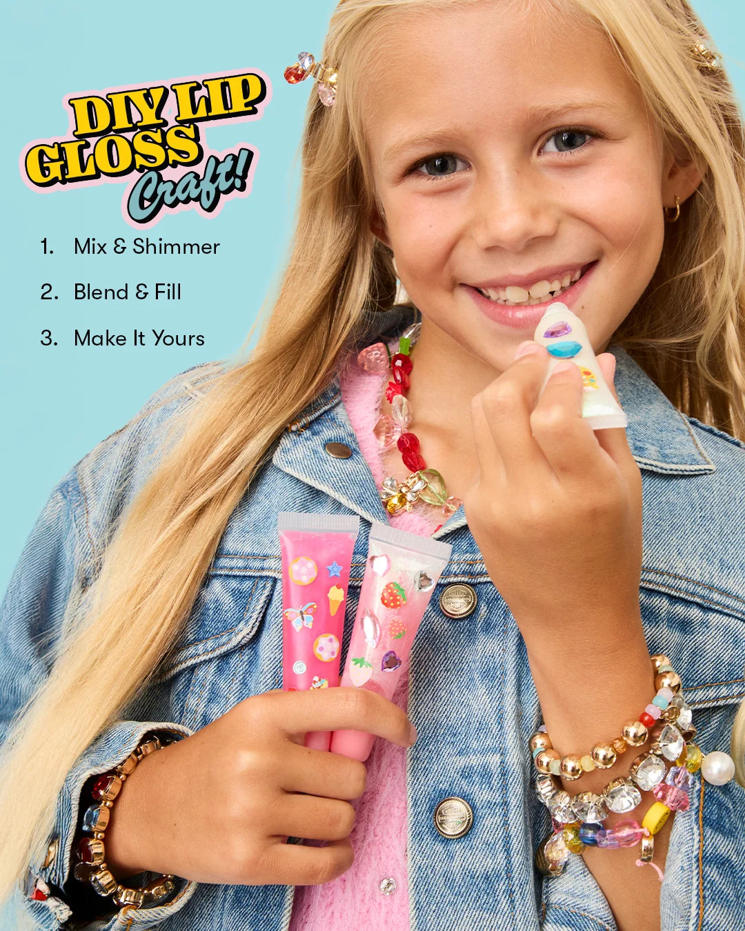 A smiling girl in a denim jacket holds tubes of lip gloss and a mixing tool. Text on the image shows steps for a DIY gloss project: Mix & Shimmer, Blend & Fill, Make It Yours. The Super Smalls Create Your Own Lip Gloss kit features kid-safe ingredients and invites kids to get creative with every unique gloss they make.
