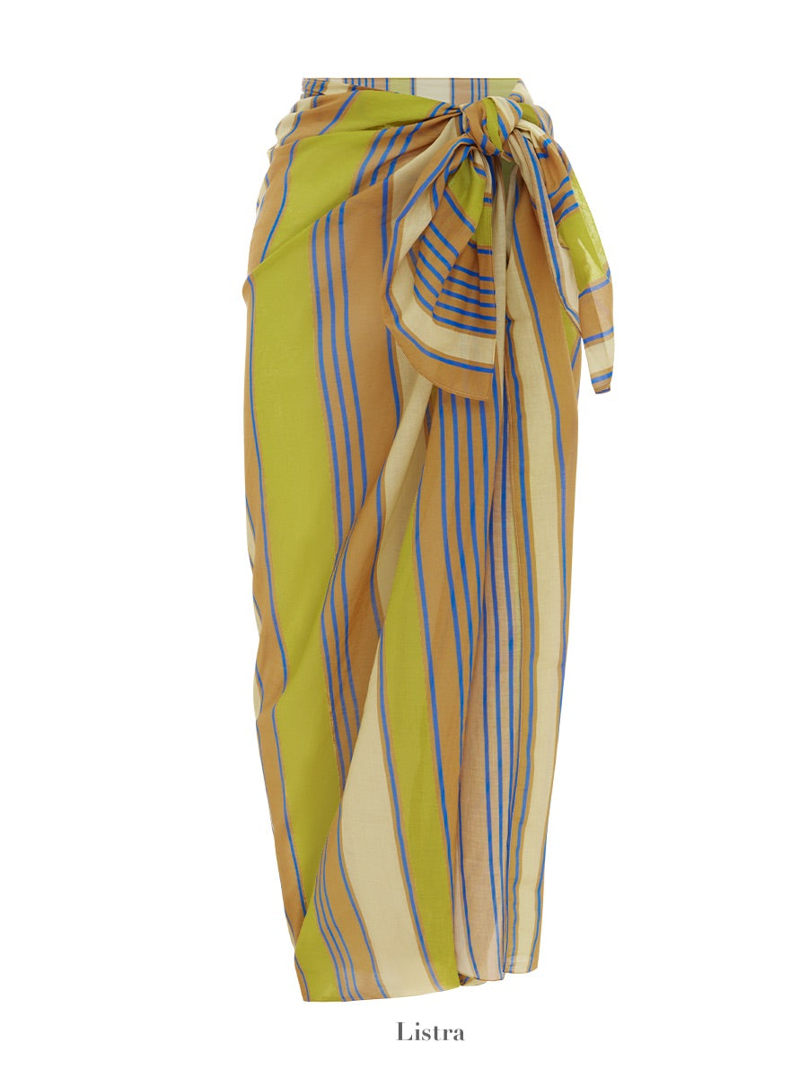 The Soleil Soleil Square Pareo is a multi-colored striped wrap skirt in organic cotton, featuring a tie around the waist and displayed against a white background. The stripes are primarily yellow, blue, and beige. The word "Soleil Soleil" is written at the bottom. Perfect as a beach cover-up or versatile piece for any occasion.