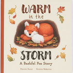 Cover of a giftable hardback children's book titled "Jellycat Warm in the Storm Book: A Bashful Fox Story" by Harriet Stone and illustrated by Kristin Makarius, featuring an illustration of a fox surrounded by autumn leaves. Perfect for a cozy bedtime story, from Jellycat.