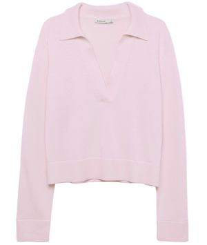The Simkhai Cashmere LS Polo Sweater in light pink features long sleeves, a deep V-neck with collar, and ribbed cuffs and hem, shown against a plain white background.
