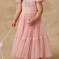 A young child in the Noralee Clara Dress—a pink, glittery dress with smocked bodice, puffed sleeves, and bow detail—holds a wand while standing against a beige background.