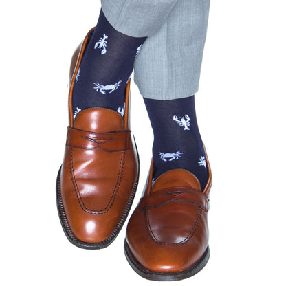 Brown leather loafers paired with expertly knitted Dapper Classics Lobster and Crab Mid Calf Socks in navy and white, worn with light gray trousers.