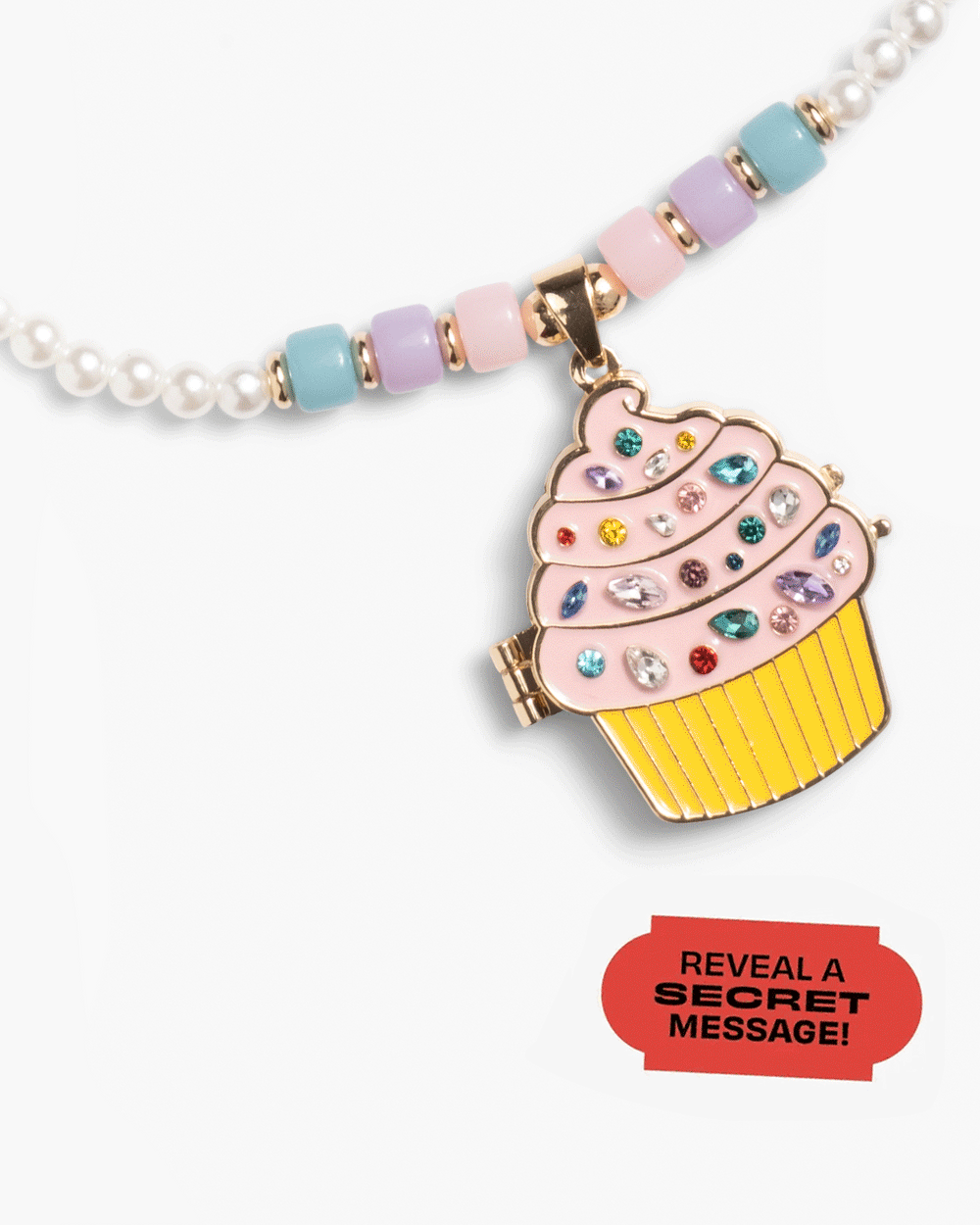 The Super Smalls Cupcake Lipgloss Locket is a beaded kids necklace featuring a cupcake-shaped keepsake locket with colorful gems and a red label that says, "REVEAL A SECRET MESSAGE!.
