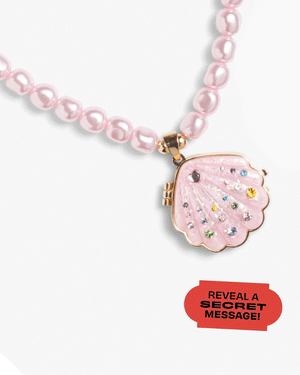 The Super Smalls Sparkle Shell Lipgloss Locket is a pink beaded necklace featuring a seashell-shaped jeweled locket. A red label reads, "REVEAL A SECRET MESSAGE!.