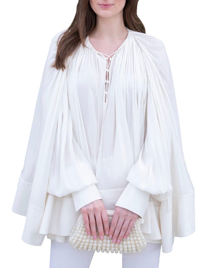 A person in a white, flowing **Lanvin Long Sleeve Blouse Open Neck** holds a pearl-embellished clutch, exuding an air of elegance reminiscent of Lanvin's timeless style.