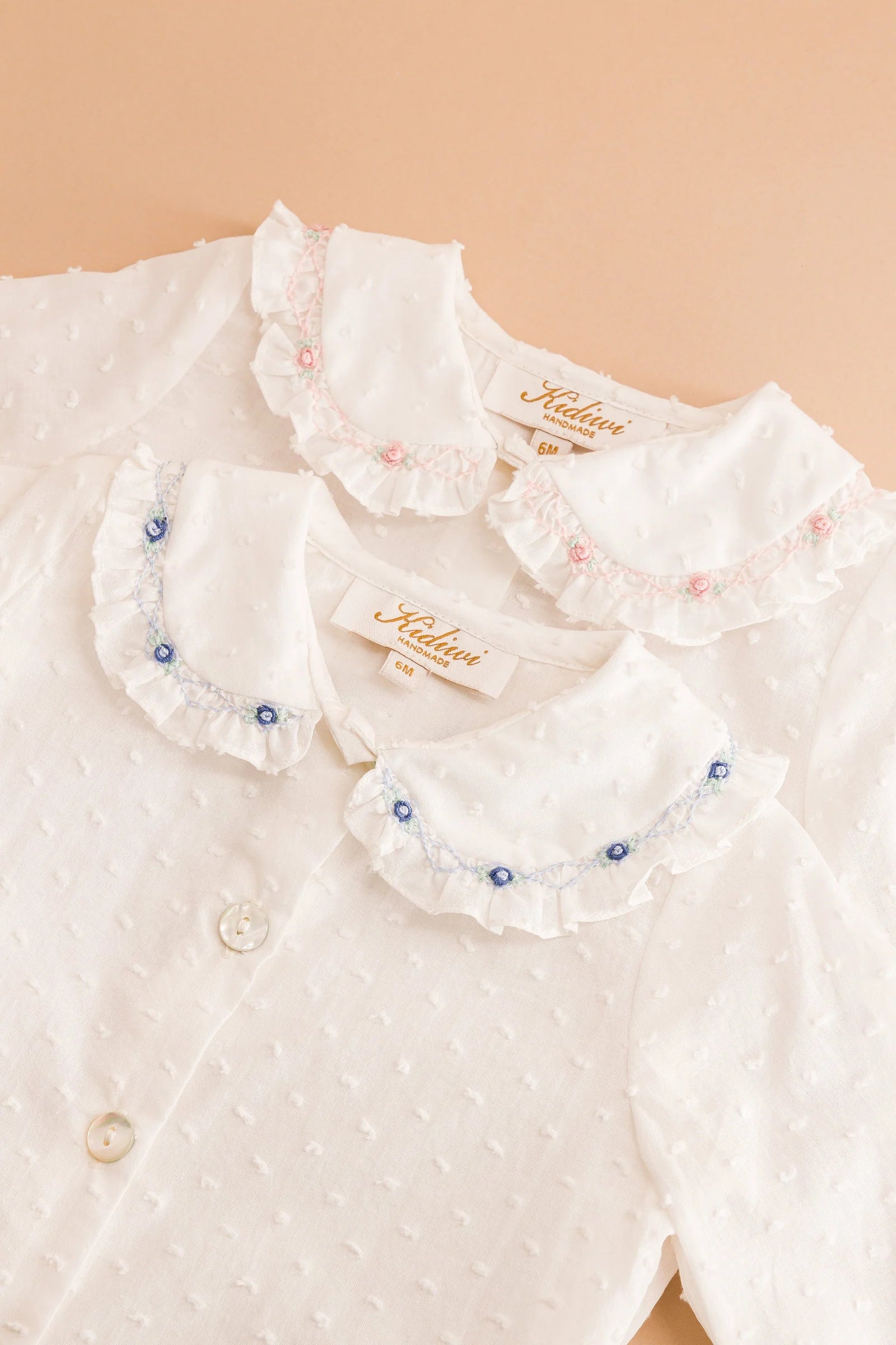 The Kidiwi Baby Girls' Lorena Blouse features off-white plumetis fabric and a delicate Peter Pan collar.